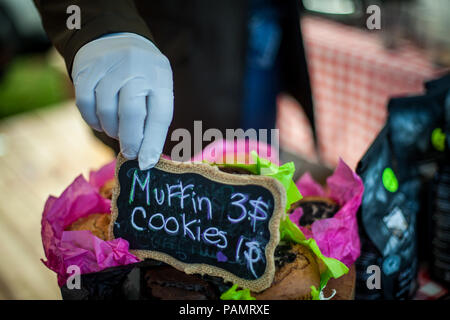 Hand mit Handschuh einen Preis auf einem Muffins und Kekse Fach bei Farmer's Market Stockfoto
