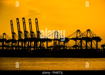 Singapur, Singapur - 23 April, 2017: Die mechanische Krane von Singapurs Hafen sitzen, während ein feuriges Orange Silhouette Silhouette. Stockfoto