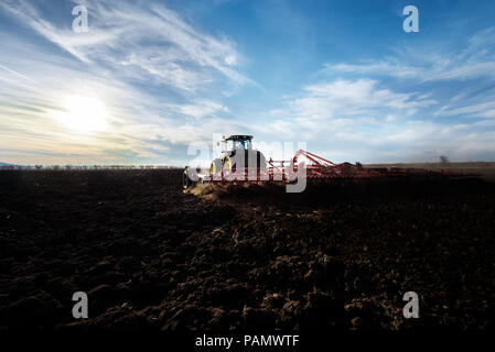 Bauer im Traktor Vorbereitung land mit saatbeet kultivator als Teil der Aussaat Aktivitäten im frühen Frühjahr Saison der landwirtschaftlichen Arbeiten. Stockfoto