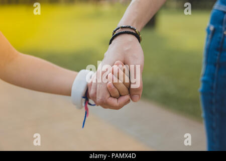 Liebevolle moderne Mutter tragen schwarz Armband ihre Tochter Holding Stockfoto