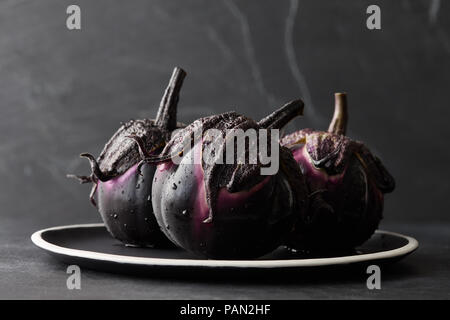 Frische Auberginen mit Wassertropfen Nahaufnahme auf schwarzem Hintergrund Stockfoto
