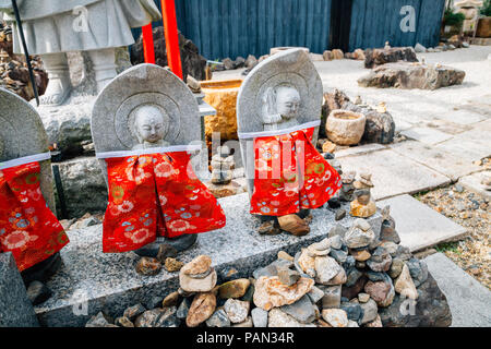 Buddha Statue aus Stein das Tragen der roten Schürze in Kyoto, Japan Stockfoto