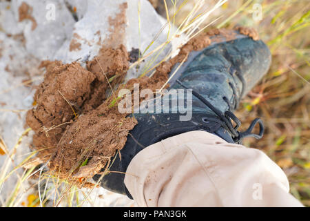 Die Sohlen der Turnschuhe voller Schlamm aus ein Wanderer in Feld im Regen. Konzept der Wandern in den Frühling. Stockfoto