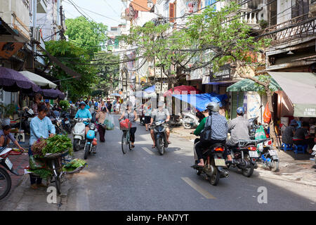 Ein traditionelles streert in der Altstadt von Hanoi, Vietnam, mit Strassenhändlern, Radfahrer und mopedfahrer. Stockfoto