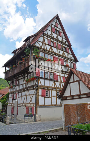 6-stöckiges Fachwerkhaus traditionelle Haus in der Deutschen Schwäbische Alb Region. Neben einem Kanal gebaut. Eine gefederte Gießkanne liefert das Wasser für die t Stockfoto