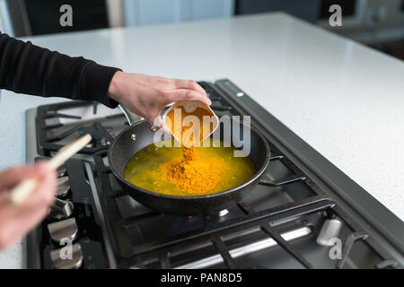 Man gießt Gelbwurz während der Vorbereitung golden Paste auf Herd Stockfoto