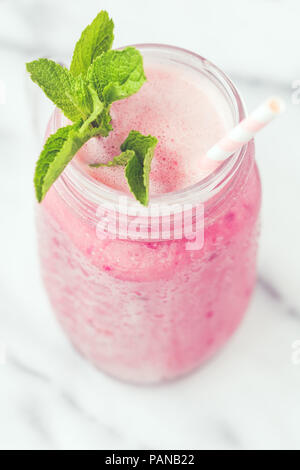 Obst rosa Smoothie in einem Glas auf einem weißen Marmor. Im minimalistischen Stil. Trend vintage getönt. Stockfoto