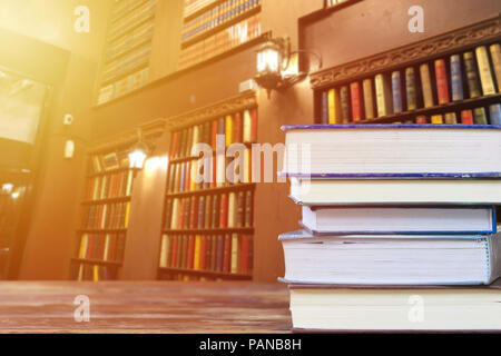 Bildung und lesen Konzept: Gruppe von Stapel Bücher auf Holztisch mit bunten Bücher im Regal in der Bibliothek als Hintergrund und Kopieren. Zurück zur Scho Stockfoto