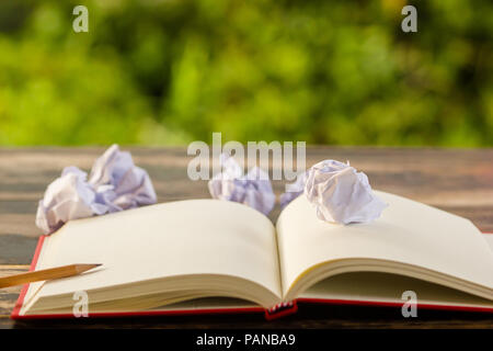 Konzept keine Idee für kreatives Denken: Zerknittertes Papier und Notiz Buch auf Tabelle mit grün Natur Hintergrund. Business Concept plan Denken. Kann nicht Crea Stockfoto