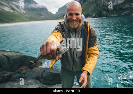 Norwegen, Lofoten, Moskenesoy, junger Mann mit frisch gefangenen Fisch Stockfoto