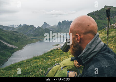 Norwegen, Lofoten, Moskenesoy, Mann an der Aussicht suchen, Trinken von Tin Cup Stockfoto