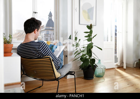 Mann, zu Hause zu sitzen, mit Laptop Stockfoto