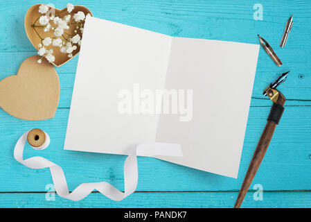 Mockup Brief mit Papier Herzen, Kraftpapier, mit Blumen für Grusskarten Valentinstag im rustikalen Stil mit Platz für Ihren Text auf einem türkis Holz- Hintergrund. Flach, Ansicht von oben Mock up Stockfoto