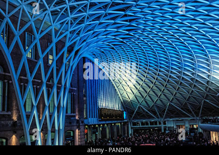 Massen von Menschen auf dem Zug für Zug in Zeiten und unter dem blauen, moderne Dach Warten am Bahnhof Kings Cross, London, England, UK. Horizontale Stockfoto