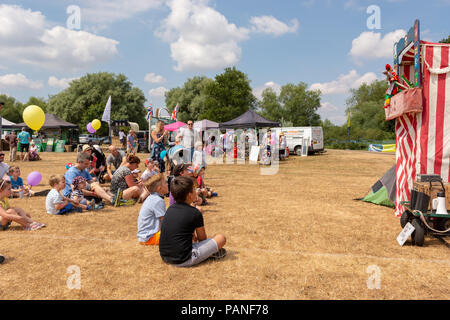 Familien und Kinder beobachten ein traditionelles Kaspertheater Puppenspiel zu einem Volksfest in Hampshire. Stockfoto
