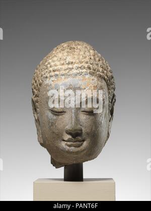 Kopf eines Buddha. Kultur: China. Abmessungen: H. 9 1/2 in. (24,1 cm); W. 6 1/4 in. (15,9 cm); D.6 1/2 in. (16,5 cm). Datum: Mid-6th century. Die subtile, deren der Wangen, Thin Nose Ridge und eleganten Schwung der Augenbrauen und Augenlider sind charakteristisch für eine Skulptur in der Provinz Shandong, im Nordosten Chinas, in der zweiten Hälfte des sechsten Jahrhunderts. Identifikation von dieser Schule der chinesischen buddhistischen Skulptur ist auf den jüngsten, spektakulären archäologischen Entdeckungen auf Websites wie Qingzhou basiert. Museum: Metropolitan Museum of Art, New York, USA. Stockfoto