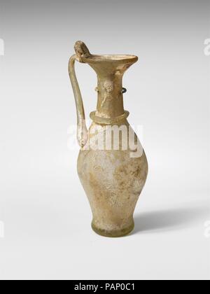 Glaskanne. Kultur: Roman. Abmessungen: H.: 4. (10,2 cm) Durchm.: 1 1/8 x 1 1/2 x 7/8 in. (2,9 x 3,8 x 2,2 cm). Datum: 4.Jahrhundert N.CHR.. Kleine Kanne. Farblos mit gelben Grðnstich, Griff und in der gleichen Farbe Trail. Rim ausgeklappt, rund, und drückte in die Seite des abfackeln Mund; zylindrische Hals nach unten erweitern und sich unmerklich mit schlanken bauchigen Körper; Dick unten, Dreschkorb in der Mitte und mit Gespreizter äusseren Rand; Griff der Stange zum oberen Körper in einem Kratzte Pad befestigt ist, nach oben und leicht nach außen gezogen, dann in stark auf der Felge gedreht, mit vorgezogener oben eingeklemmt Falten. Um den Hals, s Stockfoto