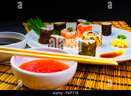 Frisch und lecker Sushi japanisches Essen. Bild von der japanischen Küche. Sushi Rollen auf Teller serviert in einem Restaurant. Kopieren Sie Platz. Schwarzen Hintergrund. Stockfoto