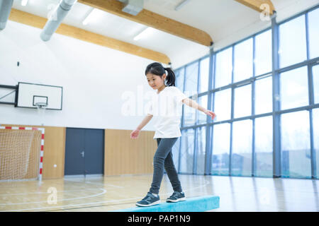 Schulmädchen Balancieren auf Schwebebalken in der Turnhalle Klasse Stockfoto