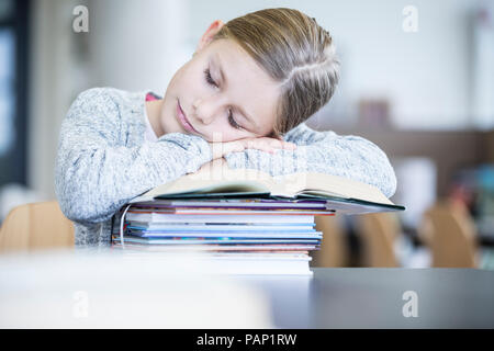 Schulmädchen schlafen auf der Bücher auf dem Tisch stapeln in der Schule Stockfoto