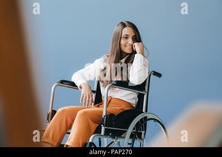 Junge behinderte Frau sitzt im Rollstuhl, lächelnd Stockfoto