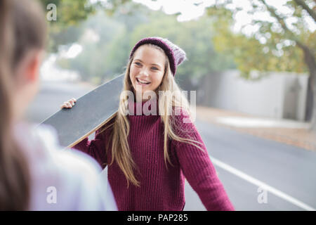 Lächelnd Jugendmädchen Holding skateboard Treffen mit Freund Stockfoto