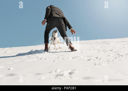 Mann spielt mit Hund im Winter, Spaß im Schnee Stockfoto