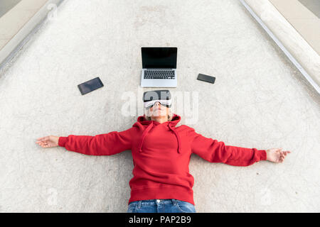 Ältere Frau auf dem Boden liegend tragen VR-Brille neben mobile Geräte Stockfoto