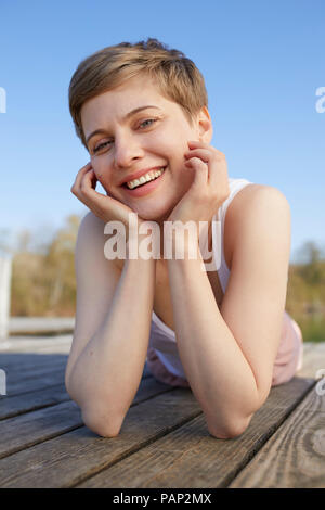 Porträt der lächelnde Frau liegend auf Jetty Stockfoto