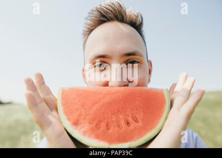 Porträt eines jungen Mannes mit einer Wassermelone im Freien Stockfoto