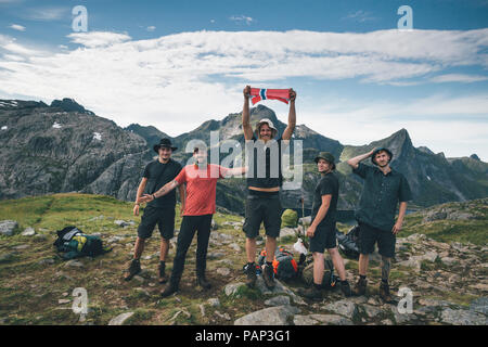 Norwegen, Lofoten, Moskenesoy, einer Gruppe von jungen Männern Jubel mit norwegischer Flagge Stockfoto