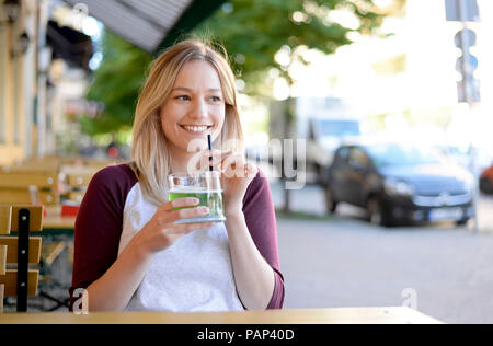 Blonde junge Frau trinkt "Berliner Weiße" im Biergarten Stockfoto