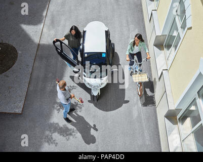 Drei Personen mit elektrischen Bubble Car, Skateboard und Fahrrad Stockfoto