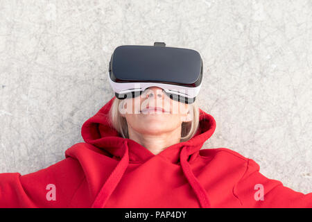 Ältere Frau auf dem Boden liegend tragen VR-Brille Stockfoto