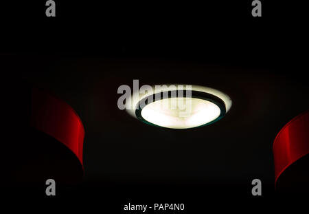 Interieur leuchten auf dunklem Hintergrund in der Nacht. Innenbeleuchtung Konzept. Runde Glas mit schwarzem Ring Abdeckung der Deckenleuchte. Stockfoto