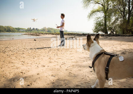 Mann mit Hund flying Drone an einem Fluss Stockfoto