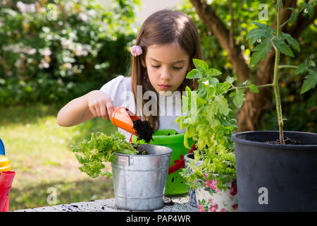 Portrait von kleinen Mädchen Blumenerde Petersilie auf Tisch im Garten Stockfoto