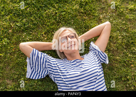 Portrait von lächelnden älteren Frau im Gras liegend Stockfoto