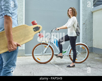 Mann und Frau, die mit Skateboard und Fahrrad Stockfoto