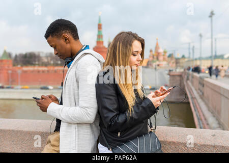 Russland, Moskau, Gemischtrassiges Paar mit Smartphones in der Stadt Stockfoto