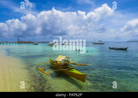 Rustikal gelb Fischerboot am Strand an einem sonnigen Tag, mit beeindruckenden Wolkenbildung über dem tropischen Insel Siargao, Philippinen Stockfoto