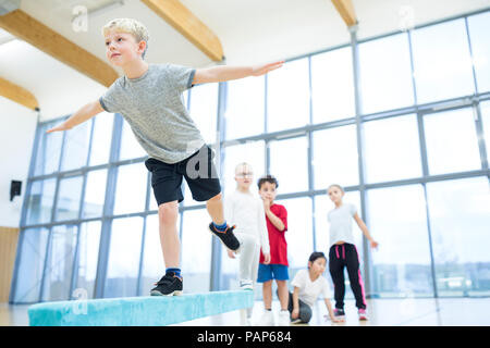 Schüler Balancieren auf Schwebebalken in der Turnhalle Klasse Stockfoto