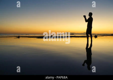 Profil von touristischen Mann Fotos auf der Insel Strand während der schönen orange Sonnenuntergang - Panglao, Bohol, Philippinen Stockfoto