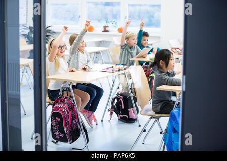 Glückliche Schüler heben ihre Hände in der Klasse Stockfoto