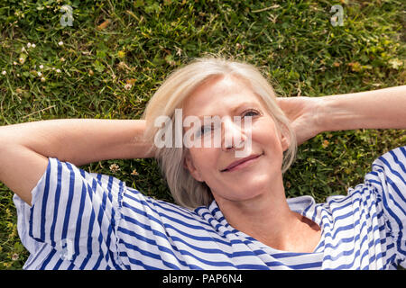 Portrait von lächelnden älteren Frau im Gras liegend Stockfoto