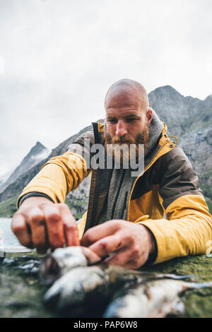 Norwegen, Lofoten, Moskenesoy, junge Männer Reinigung frisch gefangenen Fisch bei Horseid Strand Stockfoto