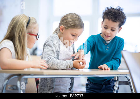 Drei Schüler der Klasse streicheln Maus Stockfoto