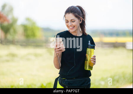 Sportliche Frau mit Smartphone beim Kühlen Pause Stockfoto