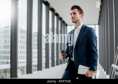 Junge Unternehmer stehen in einen Durchgang mit Kaffee und Zeitung zum Mitnehmen Stockfoto