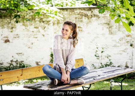 Portrait von lächelnden Frau sitzt am Biertisch im Courtyard Stockfoto